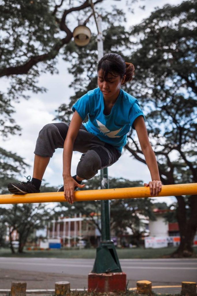 Woman in a blue shirt vaulting over a yellow rail